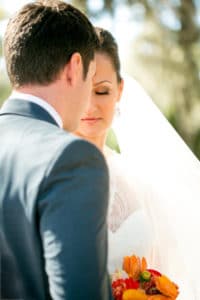 Bride and groom facing each other. The groom is facing away from the camera and the bride's eyes are closed