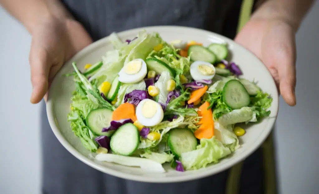 Woman's hands holding bowl of salad