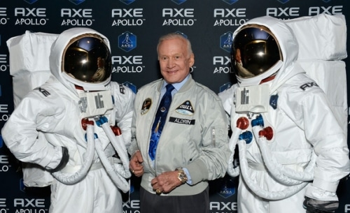 Buzz Aldrin standing with two space suits