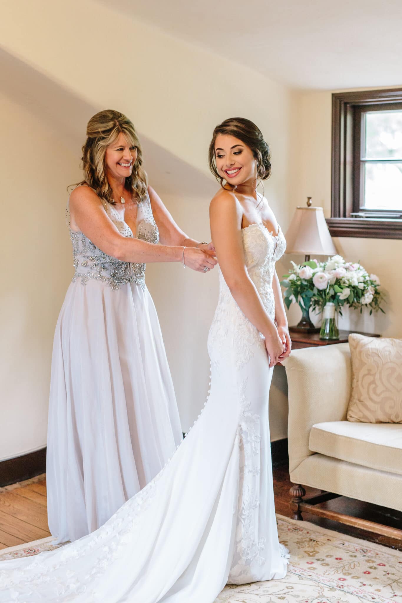 A bridesmaid helping a bride into her dress