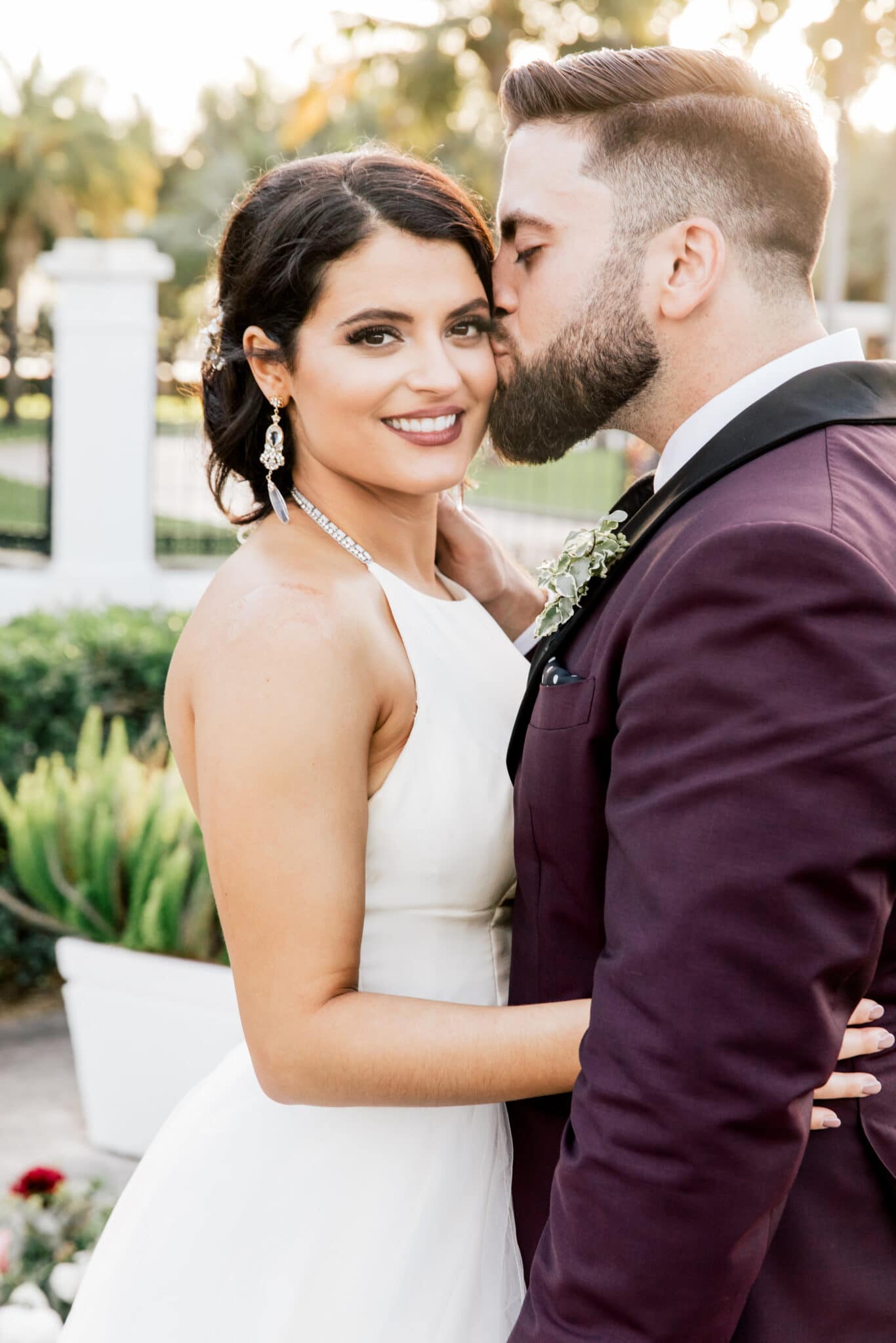 Groom kisses bride as she looks at camera