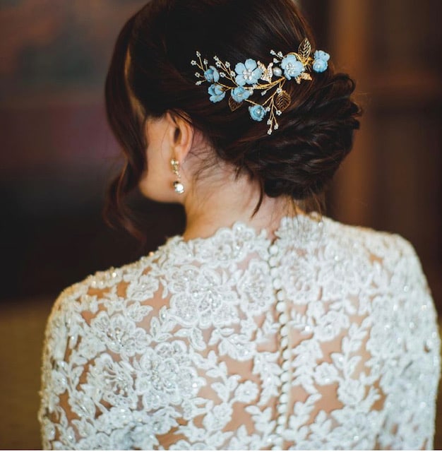 Bride facing away from the camera. She has a lace and beaded dress with her 'something blue' in her hair