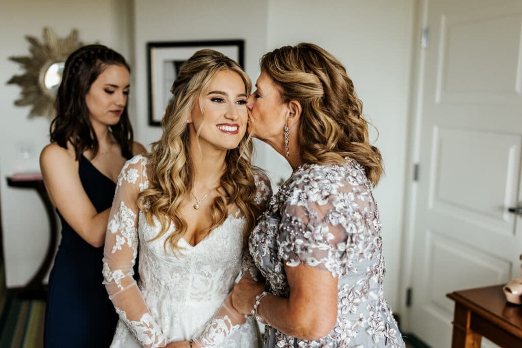 Mother of the bride kissing her daughter right before her wedding.