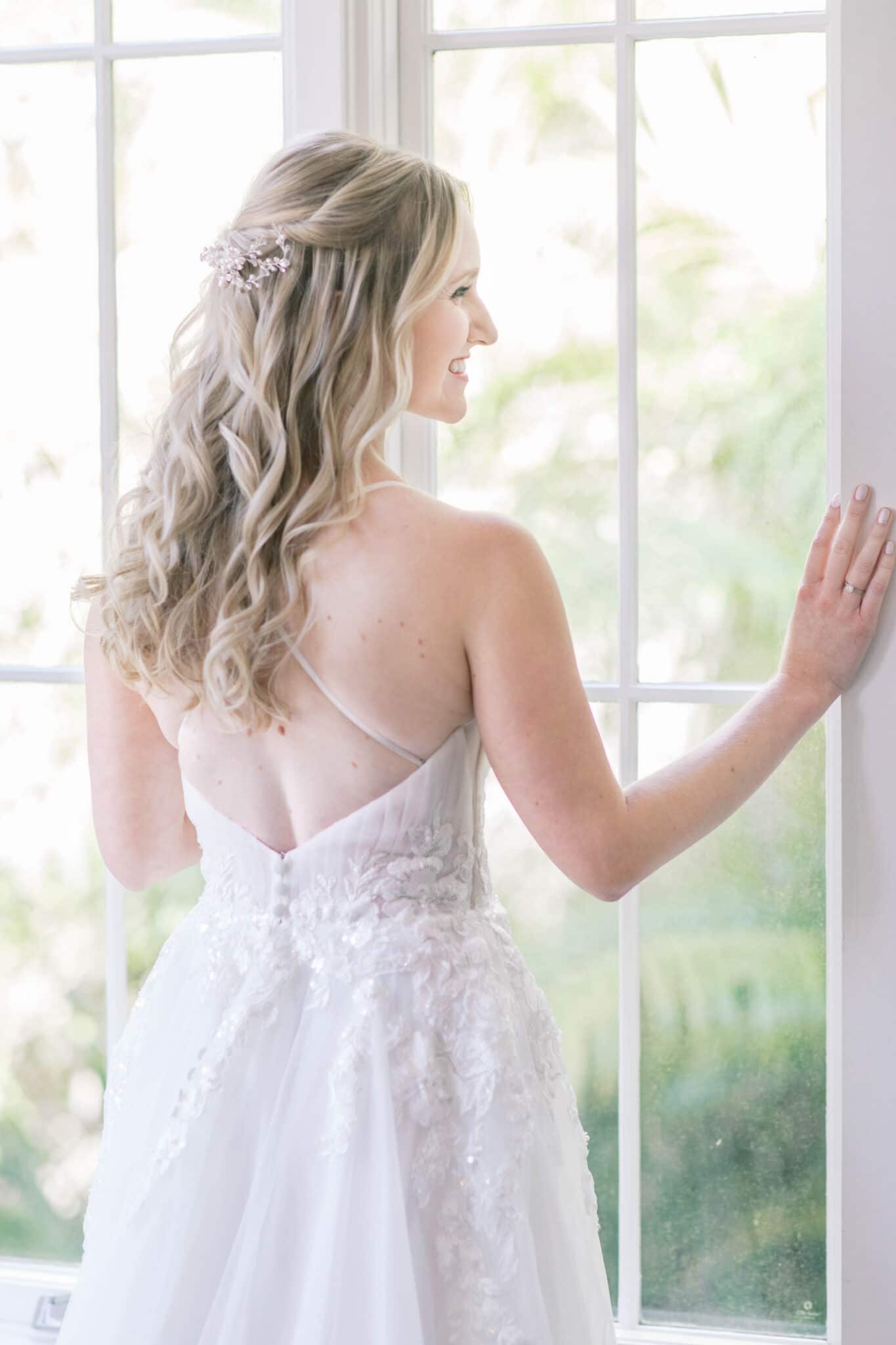 Bride smiling standing by a window.