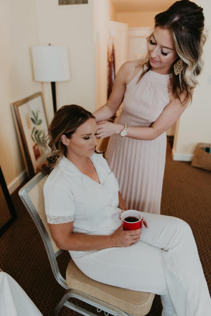 A bride sitting with her bridesmaid on wedding day.