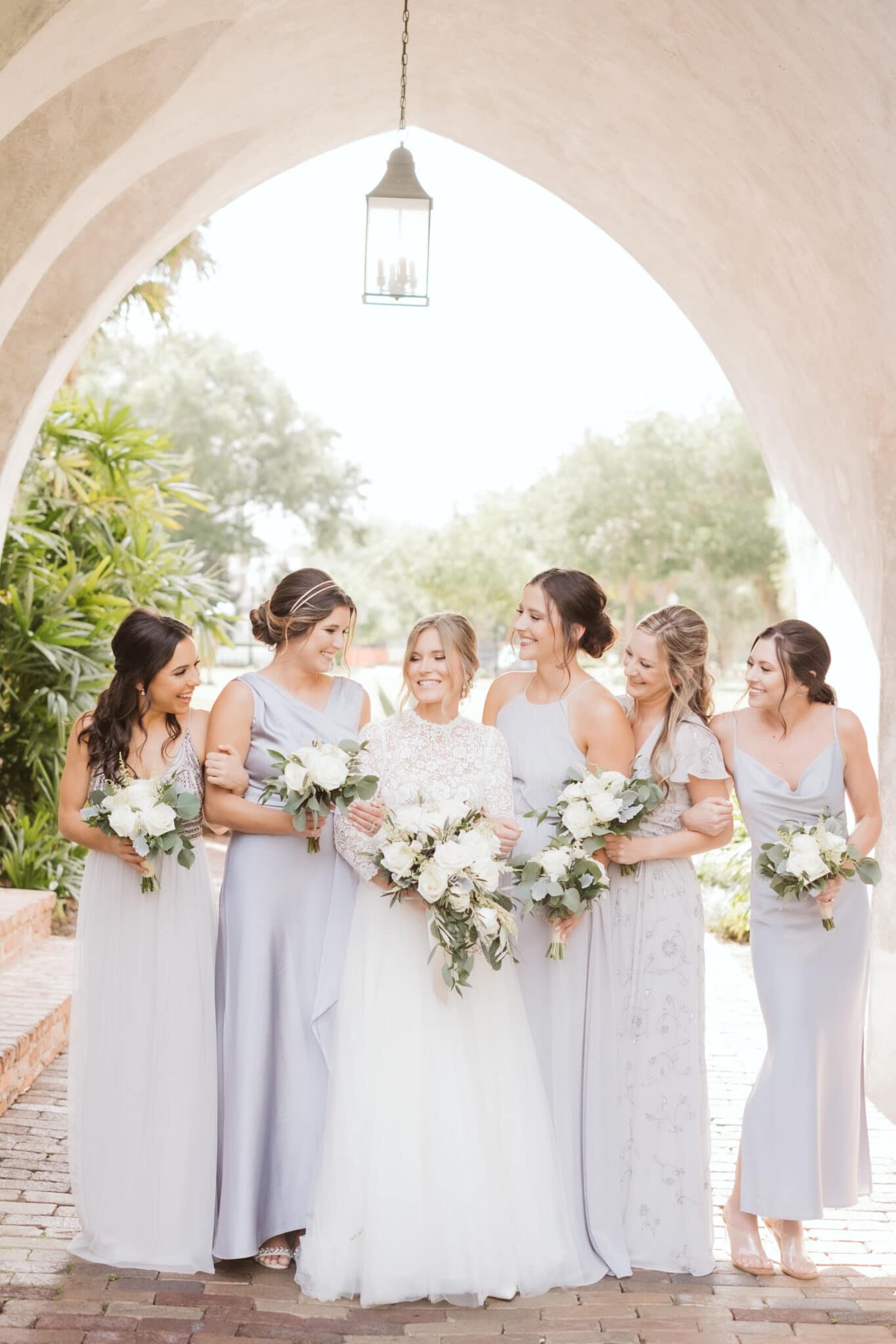 Bride standing with bridesmaids under arch