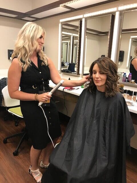 Blonde woman in a black dress doing Tina Fey's hair