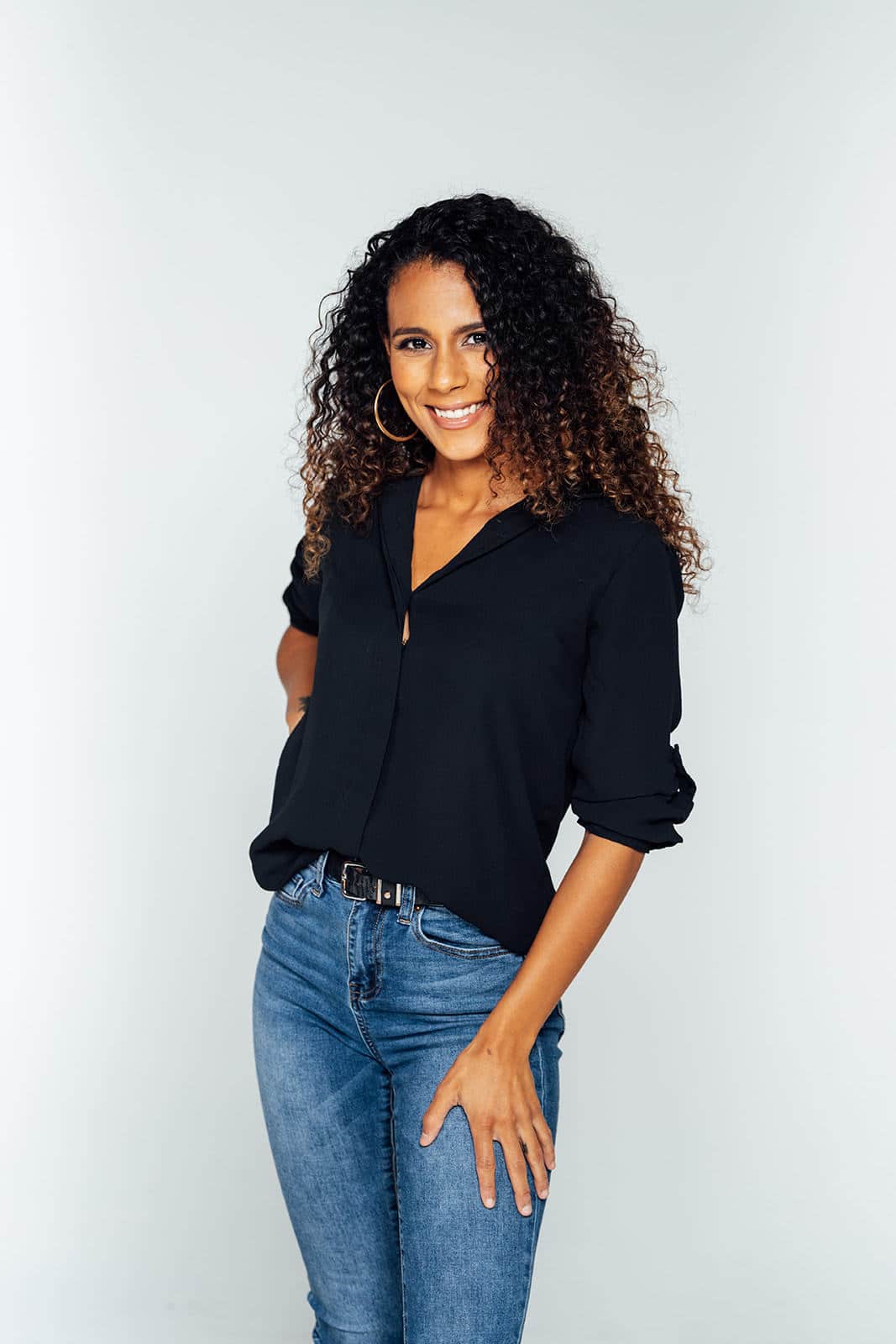 Woman with dark curly hair smiling.