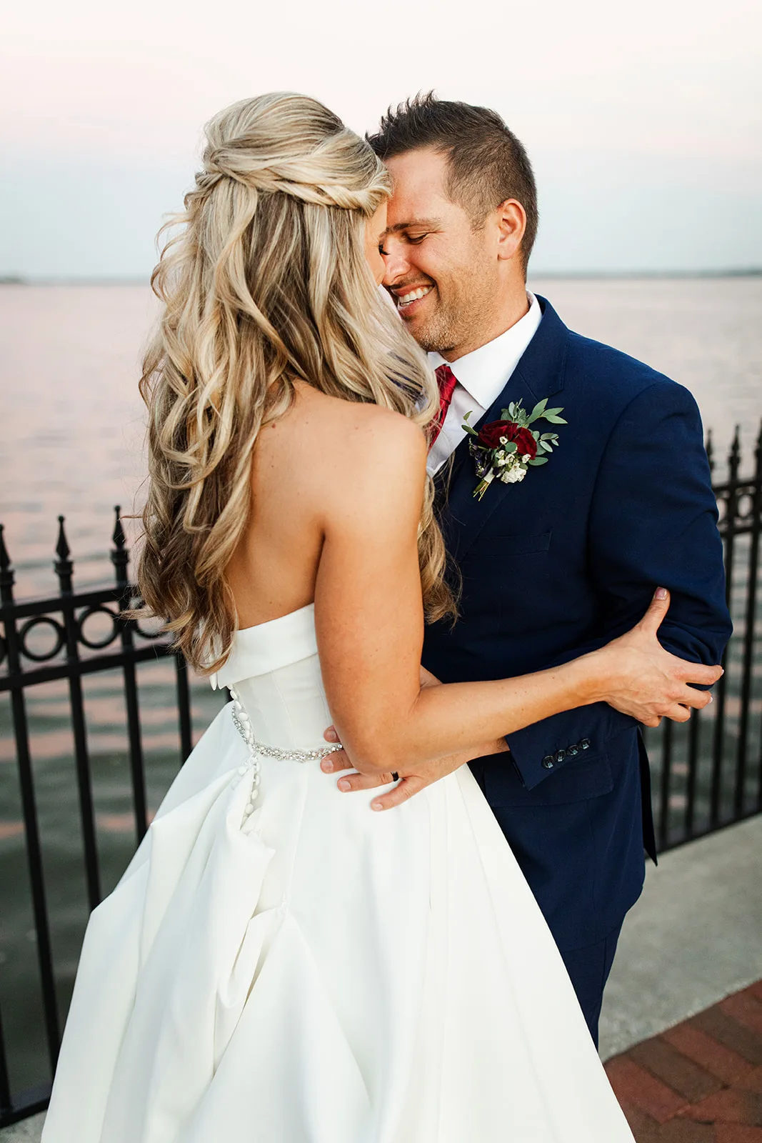 orlando wedding hair makeup bride groom portrait m3 beauty - Wedding Makeup and Hair Gallery Bride with blonde curled half-up wedding hairstyle and natural wedding makeup embracing groom in navy suit at Orlando wedding, hair and makeup by M3 Beauty